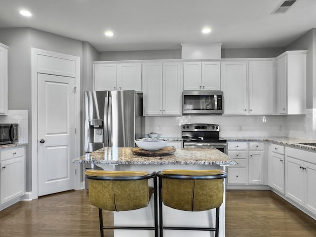 kitchen with light stone countertops, white cabinetry, and appliances with stainless steel finishes