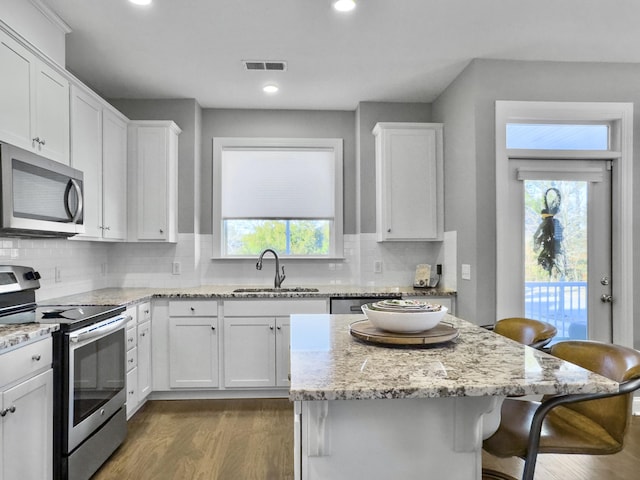 kitchen with sink, a breakfast bar area, appliances with stainless steel finishes, white cabinetry, and a kitchen island