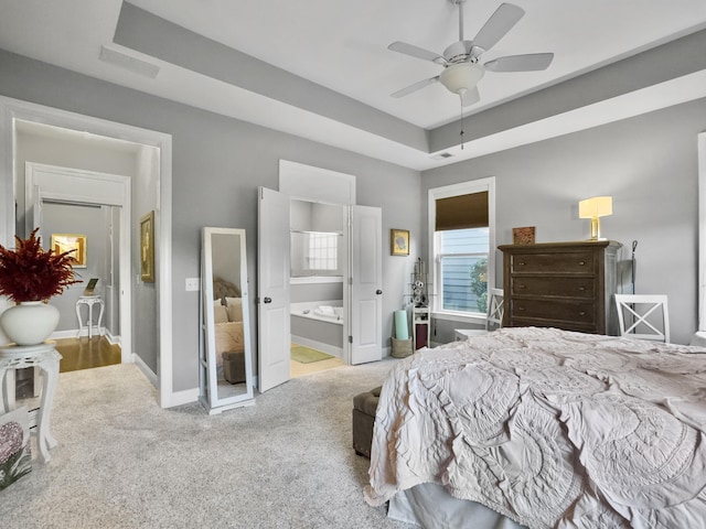 bedroom featuring ceiling fan, carpet flooring, connected bathroom, and a tray ceiling