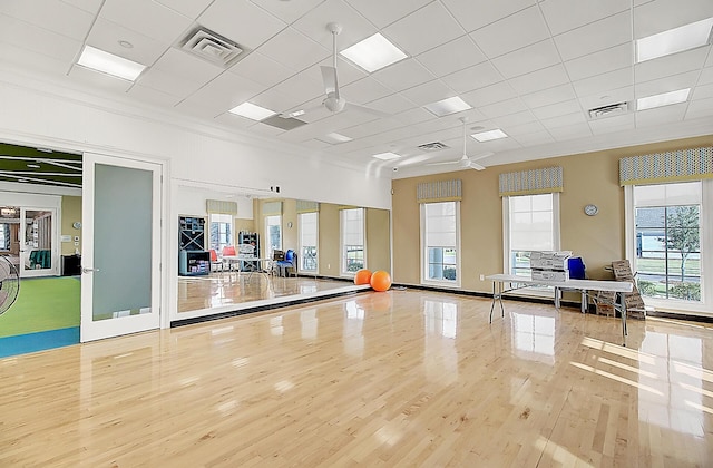 exercise area with crown molding, a drop ceiling, and light wood-type flooring