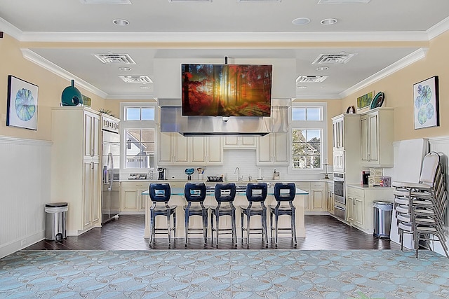 kitchen with appliances with stainless steel finishes, a kitchen island, a breakfast bar area, and cream cabinetry