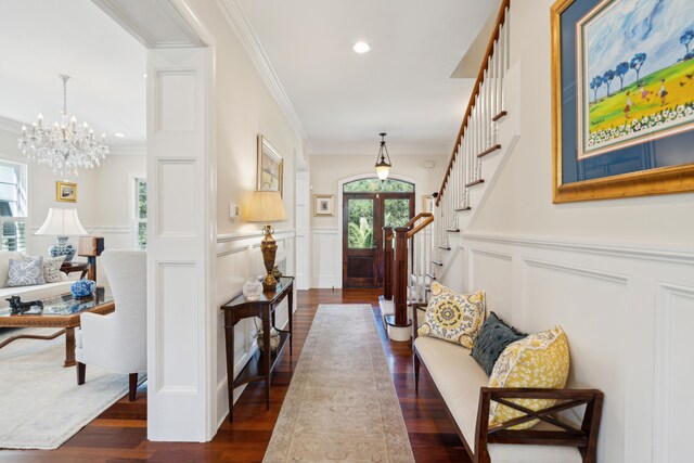 foyer with dark wood-type flooring, french doors, crown molding, and a notable chandelier