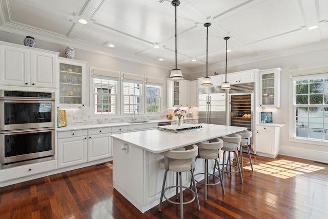 kitchen featuring hanging light fixtures, dark hardwood / wood-style floors, a kitchen island, and white cabinetry