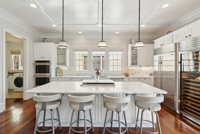 kitchen with a spacious island, washer / clothes dryer, decorative light fixtures, and dark wood-type flooring