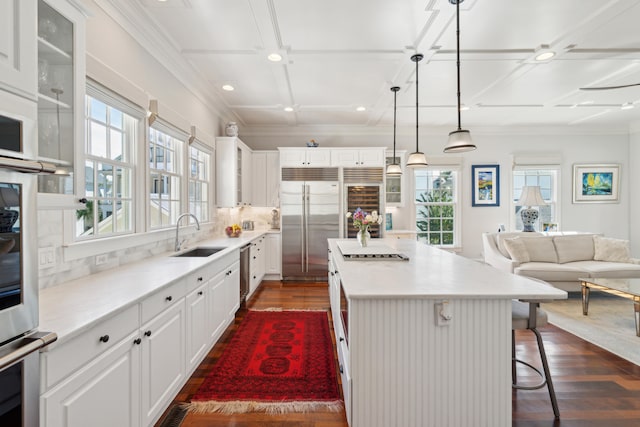 kitchen with sink, a kitchen island, dark wood-type flooring, white cabinetry, and a kitchen bar