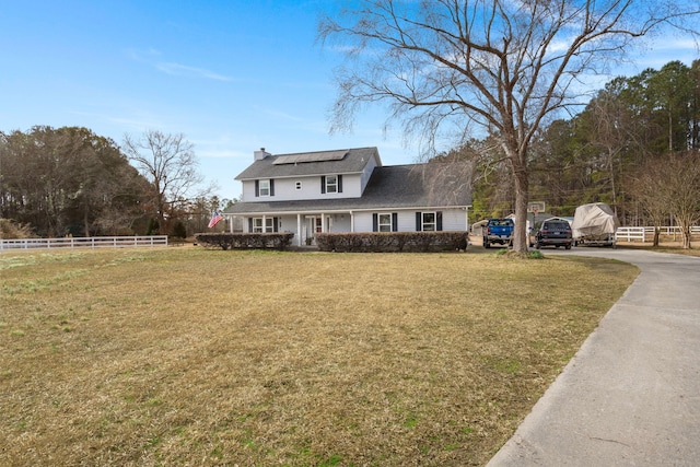 view of front of home with a front yard and solar panels