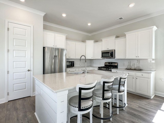 kitchen with a sink, visible vents, appliances with stainless steel finishes, decorative backsplash, and crown molding