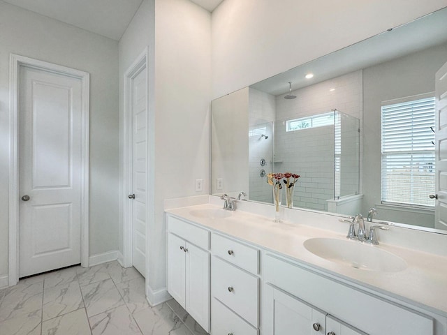 full bath with marble finish floor, tiled shower, a sink, and double vanity