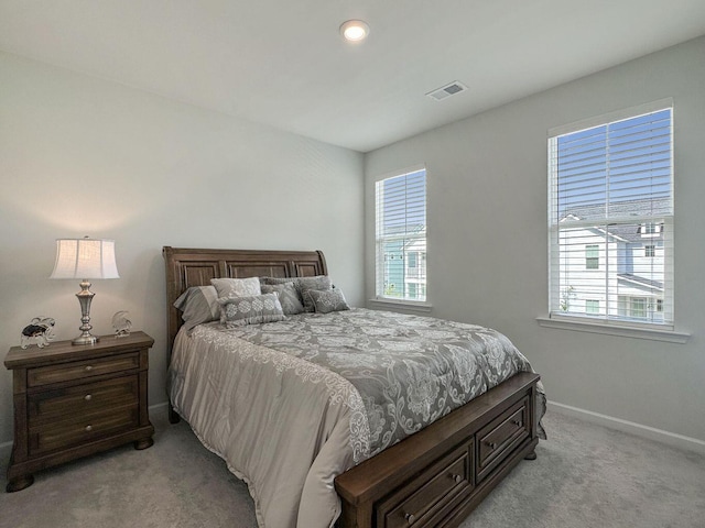 bedroom featuring light carpet, baseboards, multiple windows, and visible vents