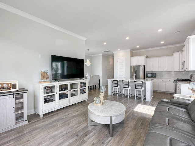 living room featuring recessed lighting, baseboards, crown molding, and light wood finished floors