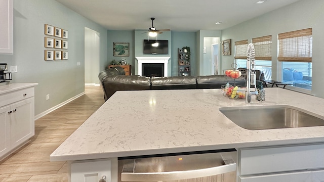 kitchen with dishwasher, sink, white cabinets, and light stone counters