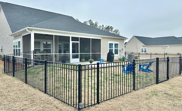 rear view of property with central AC, a yard, and a sunroom