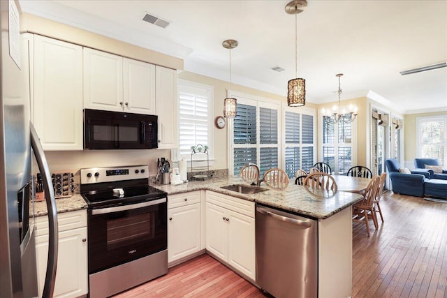 103 Grand Pavilion Blvd, Isle Of Palms, SC 29451 - kitchen featuring stainless steel appliances, visible vents, a sink, light wood-type flooring, and a peninsula