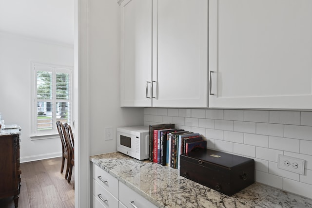 3998 Capensis Ln, Ravenel, SC 29470 - kitchen with wood finished floors, backsplash, light stone counters, white cabinets, and white microwave