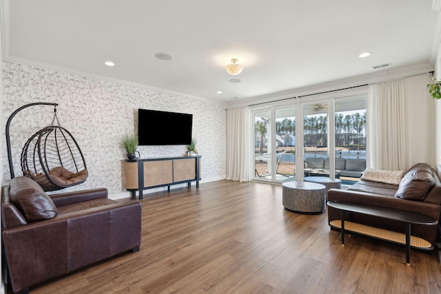 living room featuring wallpapered walls, visible vents, ornamental molding, wood finished floors, and recessed lighting