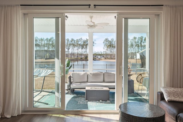 doorway to outside with a water view, ceiling fan, a wealth of natural light, and wood finished floors