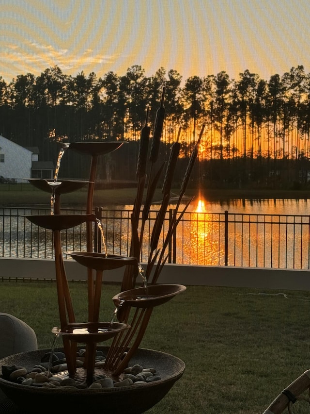 yard at dusk featuring a water view and fence