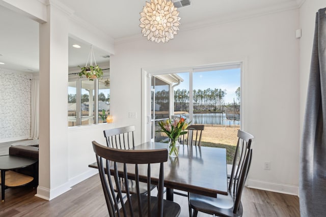 dining room featuring ornamental molding, a water view, wood finished floors, and baseboards