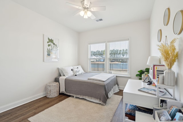 bedroom with a ceiling fan, visible vents, dark wood finished floors, and baseboards