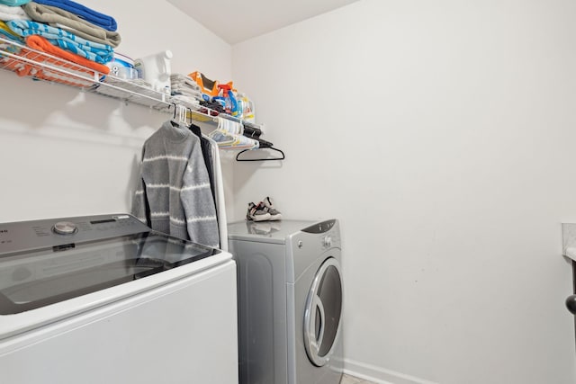 clothes washing area featuring laundry area, baseboards, and washer and clothes dryer