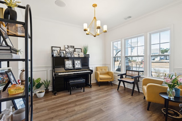 sitting room featuring crown molding, a notable chandelier, visible vents, wainscoting, and wood finished floors