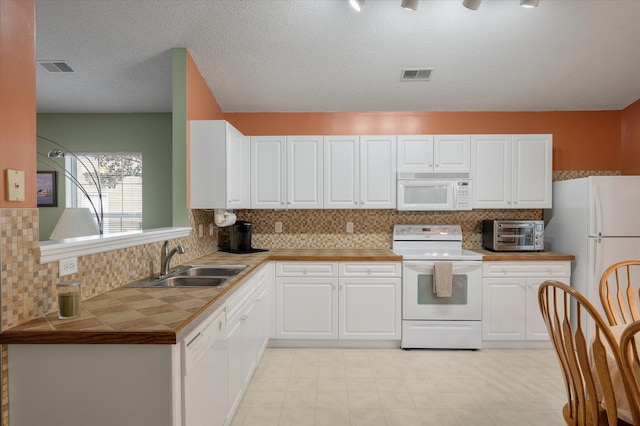 kitchen with white appliances, sink, and white cabinets