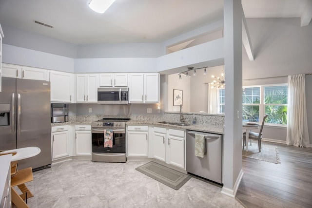 512 Castle Hall Rd, Mount Pleasant, SC 29464 - kitchen with appliances with stainless steel finishes, a sink, light stone countertops, white cabinetry, and a towering ceiling