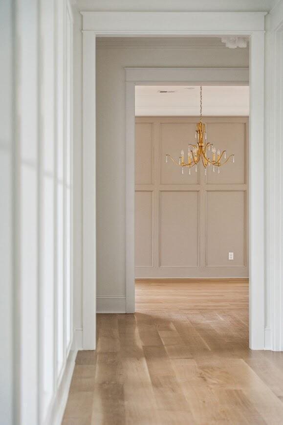 1479 Jeremy Cay Ct, Awendaw, SC 29429 - hall with a chandelier, light wood-style flooring, baseboards, and a decorative wall