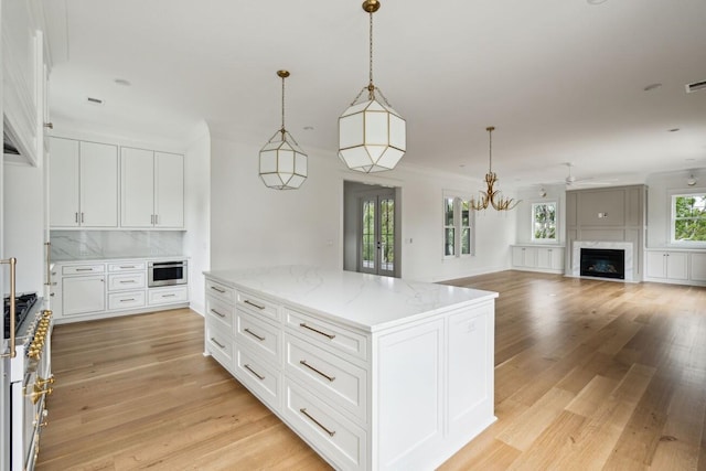 1479 Jeremy Cay Ct, Awendaw, SC 29429 - kitchen featuring light wood finished floors, a fireplace, white cabinetry, and a kitchen island