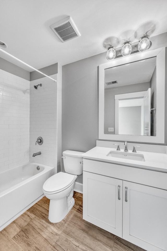 bathroom with toilet, visible vents, wood finished floors, and vanity