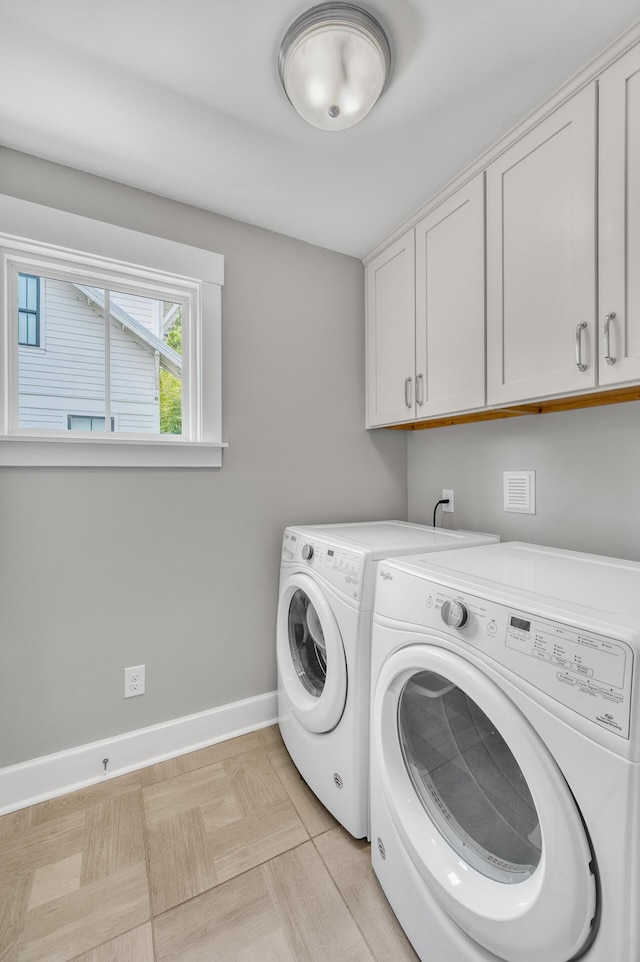 clothes washing area featuring cabinet space, baseboards, and washer and clothes dryer