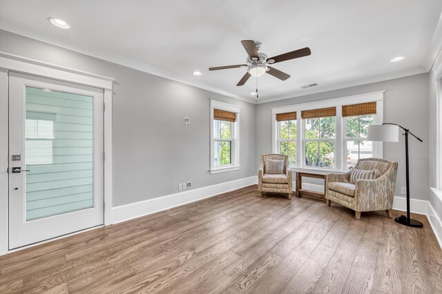 living area with ceiling fan, wood-type flooring, and ornamental molding