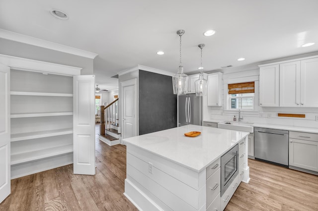 kitchen featuring light countertops, appliances with stainless steel finishes, a sink, and light wood-style floors