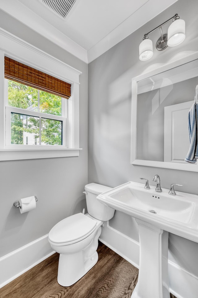 bathroom with toilet, baseboards, visible vents, and wood finished floors