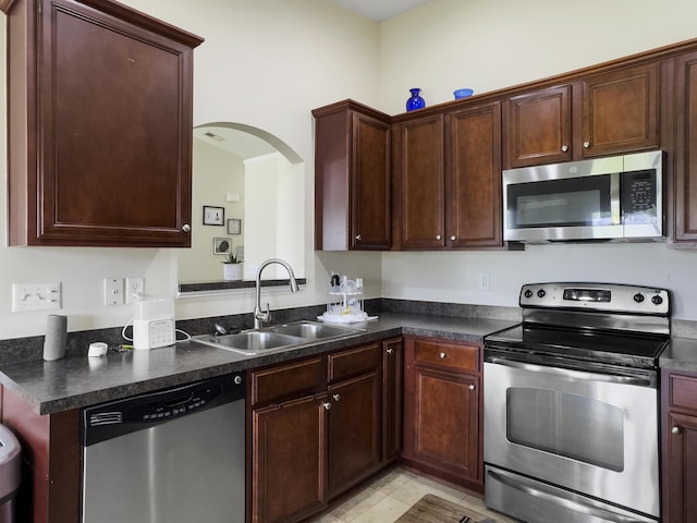 224 Market Hall St, Moncks Corner, SC 29461 - kitchen featuring appliances with stainless steel finishes, a sink, dark countertops, arched walkways, and light tile patterned floors