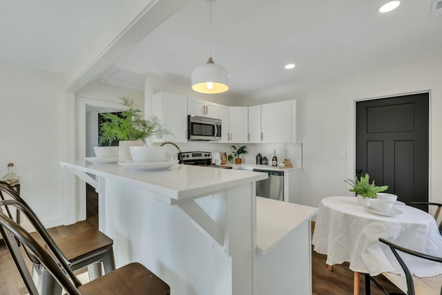 kitchen with white cabinetry, appliances with stainless steel finishes, tasteful backsplash, light wood-type flooring, and pendant lighting