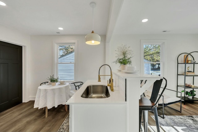 kitchen featuring decorative light fixtures, dark wood-type flooring, sink, and beamed ceiling