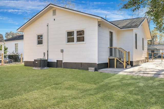 rear view of house with central AC and a yard