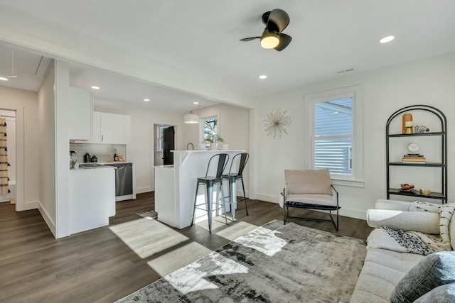 living room with ceiling fan, dark wood-type flooring, and a healthy amount of sunlight