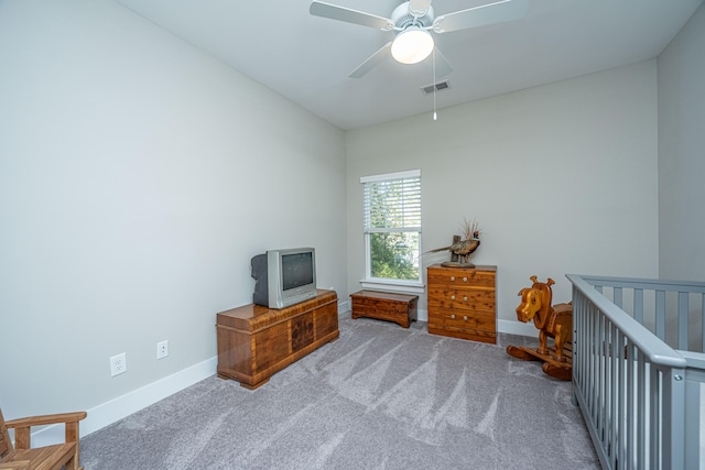 bedroom with ceiling fan, light colored carpet, and a nursery area