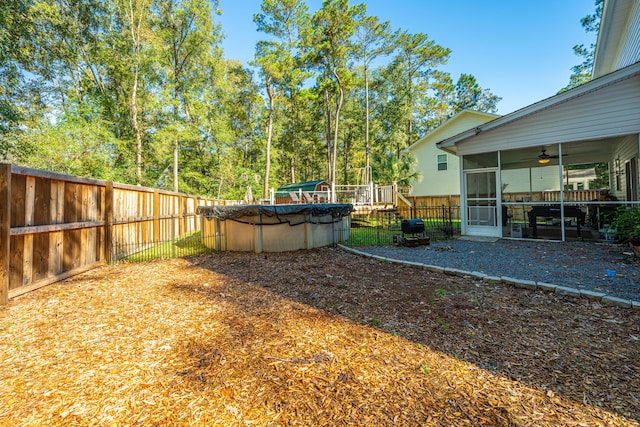 view of yard with ceiling fan, a covered pool, and a sunroom