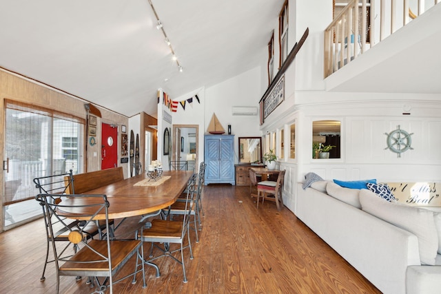 dining room with rail lighting, vaulted ceiling, and hardwood / wood-style floors