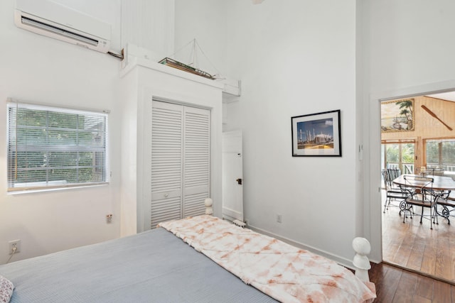 bedroom with a wall mounted AC, a closet, and multiple windows