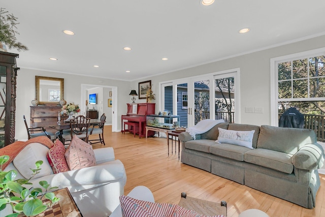 living room with light wood-type flooring, french doors, a healthy amount of sunlight, and crown molding