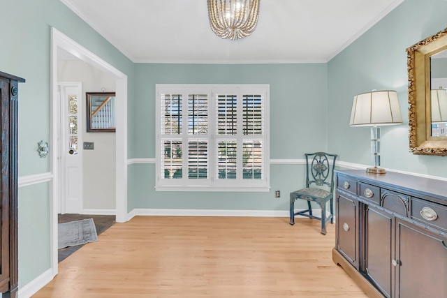 sitting room with a notable chandelier, light wood-style flooring, baseboards, and crown molding