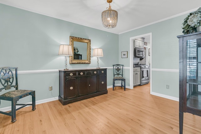 living area with crown molding, an inviting chandelier, baseboards, and light wood-style floors