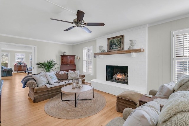 living room with a brick fireplace, light wood finished floors, and a wealth of natural light