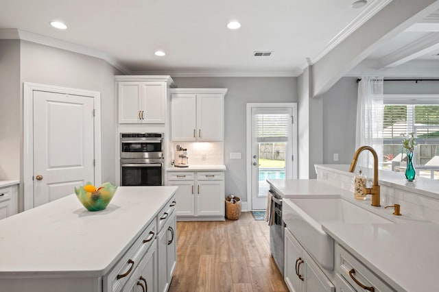 2802 Cavalcade Cir, Johns Island, SC 29455 - kitchen featuring appliances with stainless steel finishes, light countertops, light wood-style flooring, plenty of natural light, and ornamental molding