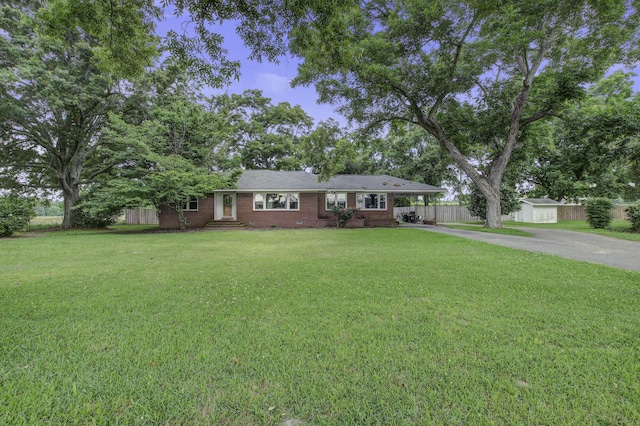 single story home featuring brick siding, a front yard, fence, a carport, and driveway