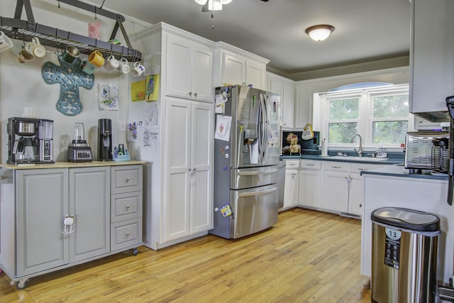 kitchen with white cabinets, light wood-type flooring, stainless steel refrigerator with ice dispenser, and a sink